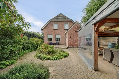 Achtertuin met klinkerterras, ronde border en de houten serre