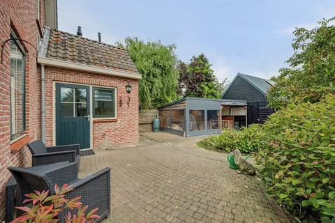 Terras naast de bijkeukendeur met zicht op de serre en de schuur