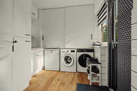 Bijkeuken met wasmachine, droger, vaatwasser, kasten en deur naar de achtertuin