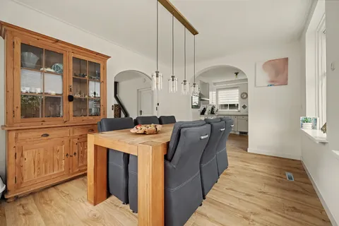 Eetkamer met houten buffetkast, eettafel en boogdoorgang naar de keuken