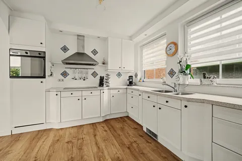 Keuken met inbouwoven, kookplaat, afzuigkap en spoelbak onder het raam