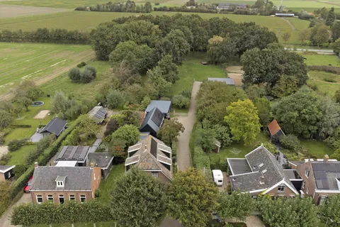Luchtfoto van de woonboerderij met zonnepanelen, de schuur en het erf