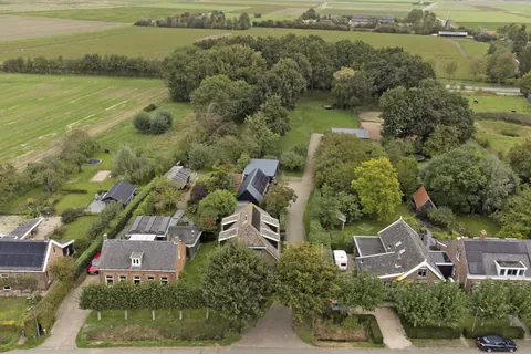 Luchtfoto van woning, schuur, carport en de oprijlaan naar de stal