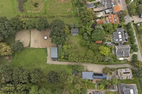 Luchtfoto recht van boven van de paardenstal, de rijbak en de weides in Nisse