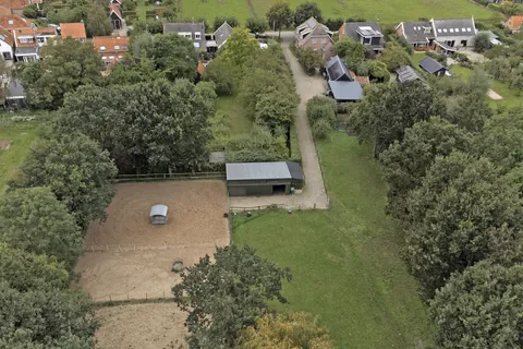 Luchtfoto van de paardenstal en de rijbak met hooiruif