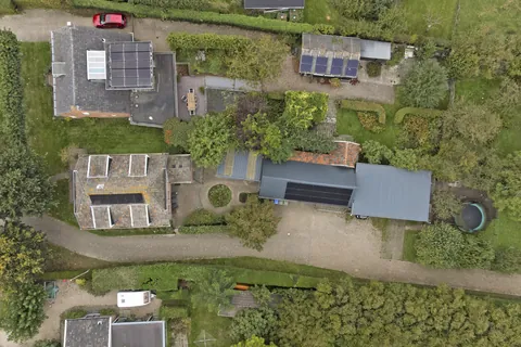 Luchtfoto recht van boven van de woning met zonnepanelen, de schuur en de carport