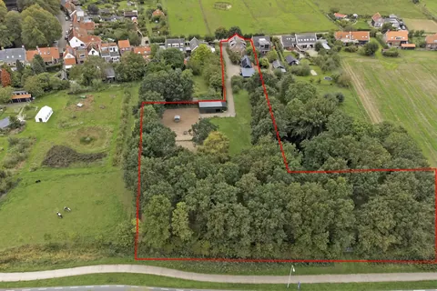Luchtfoto met de indicatieve perceelgrens van de woonboerderij in Nisse: woning, de stal, rijbak en weides