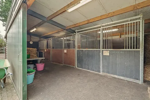 Paardenstal met drie boxen, hooiopslag en rubberen matten in de gang