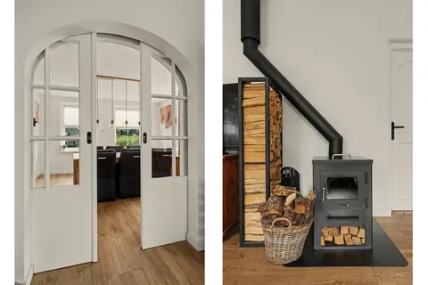 Witte schuifdeuren met glas tussen woonkamer en eetkamer, en de houtkachel met houtopslag