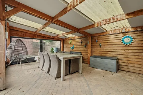 Houten serre met lichtdoorlatend dak, oprolbare wanden en een grote eettafel
