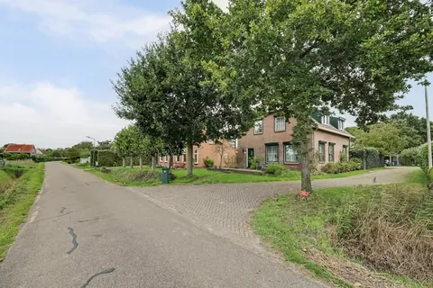 De rustige Paul Krügerstraat in Nisse met de woonboerderij en de bomen in de voortuin