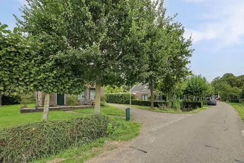 Voortuin met volwassen bomen en gazon voor de woonboerderij