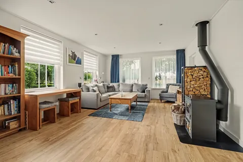 Woonkamer met houten boekenkasten, hoekbank en houtkachel