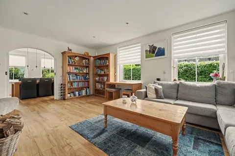 Woonkamer met boekenkasten en ronde boogdoorgang naar de eetkamer